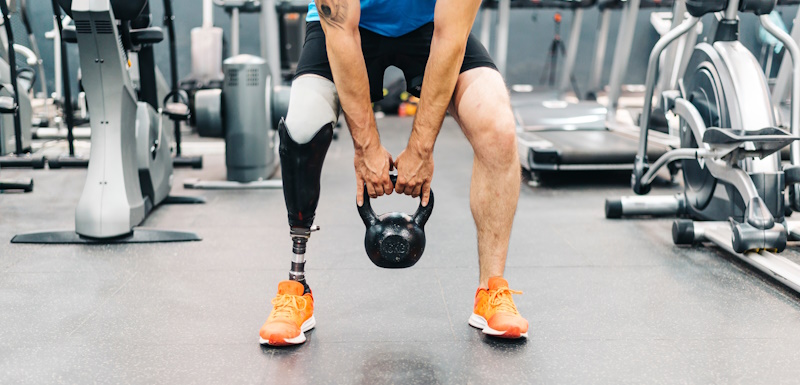 man with prosthetic leg lifting weight in gym