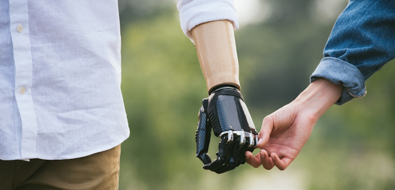 man with prosthetic arm holding hands with partner