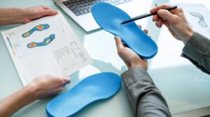 Doctor consulting patient on custom orthotic insoles in a clinic for a personalised custom fit.