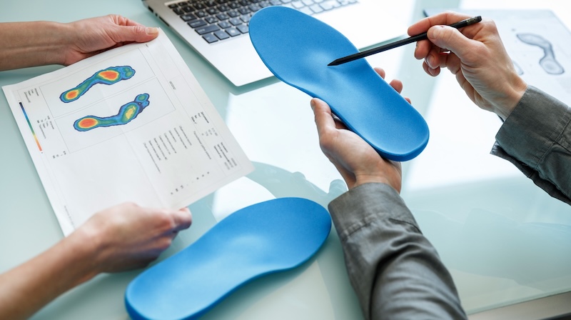 Doctor consulting patient on custom orthotic insoles in a clinic for a personalised custom fit.