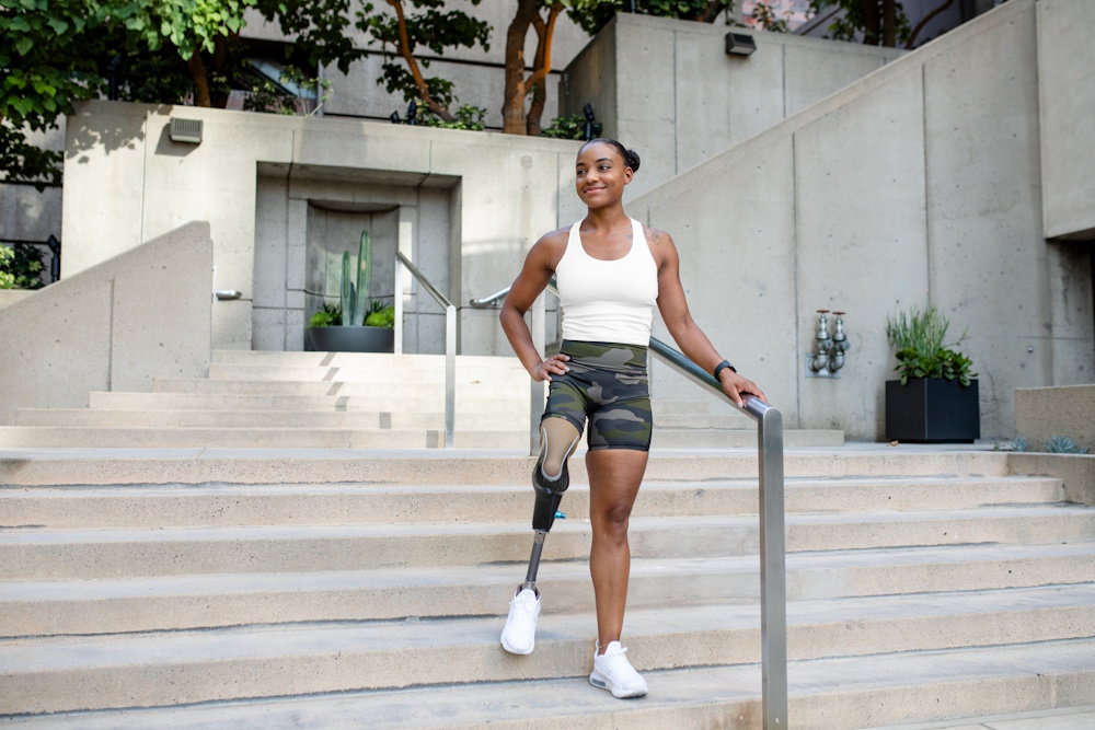 female athlete with prosthetic leg standing on stairs outside